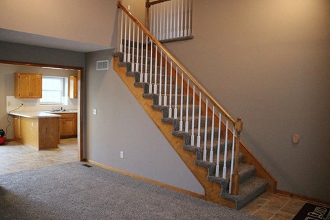 a staircase in a house with carpet and a kitchen
