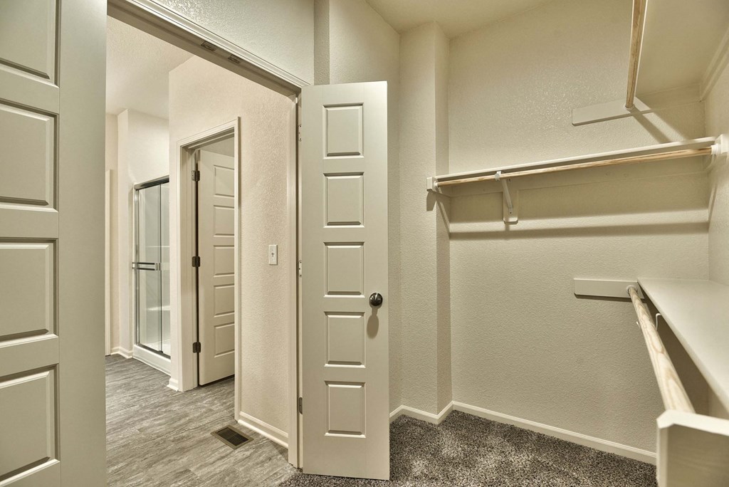 a walk in closet with a mirrored closet door and a mirrored door to a closet