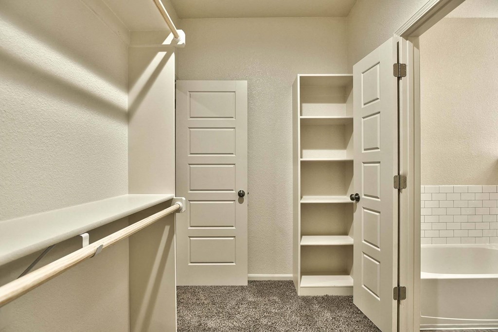 A white closet with a white door and shelves.