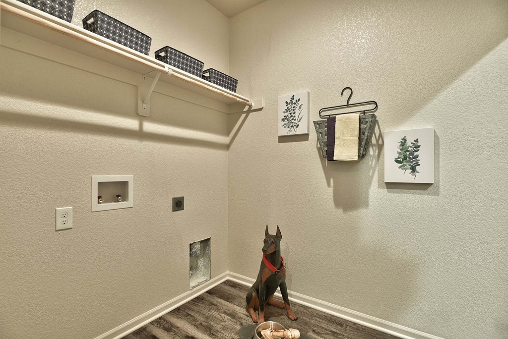 A dog sitting in a hallway with a bowl in front of it.
