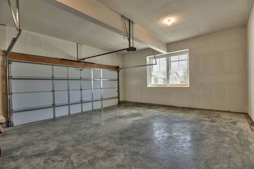 A large empty room with a garage door on the left side.