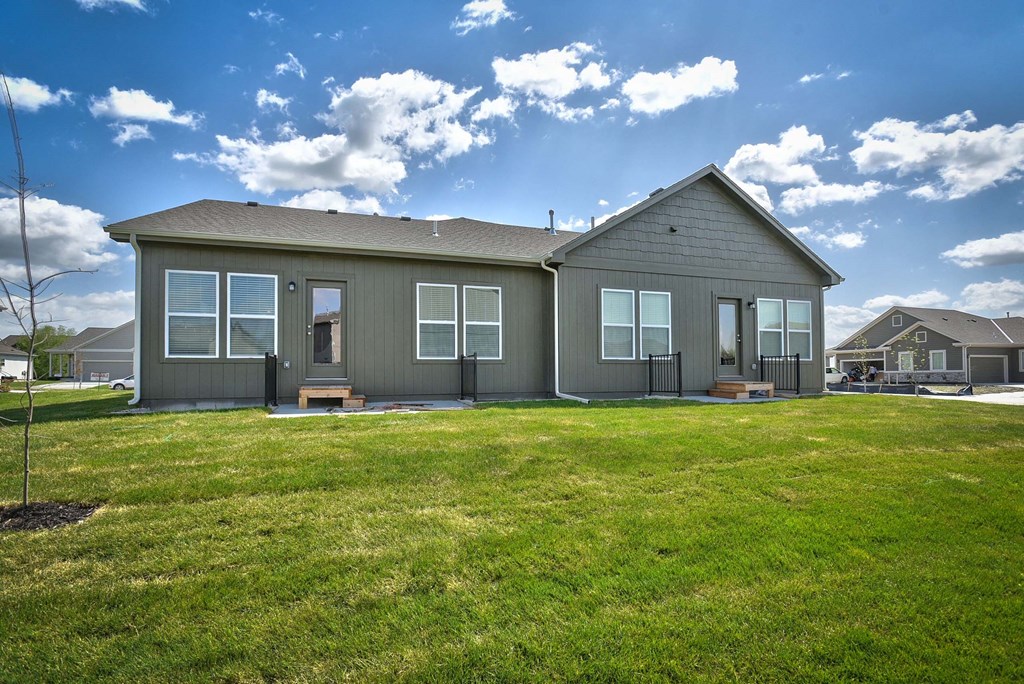 A grey house with a brown roof and a green lawn in front.