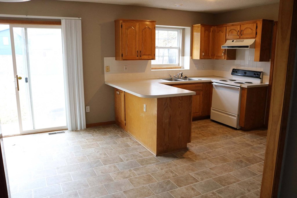 an empty kitchen with wooden cabinets and a window