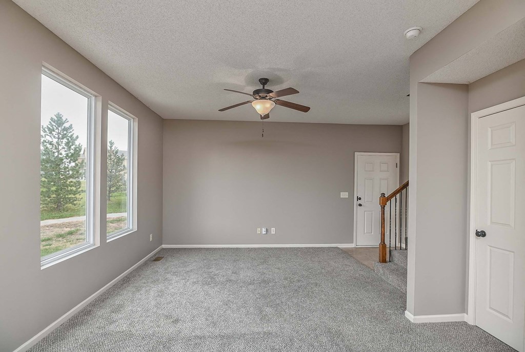 an empty living room with a ceiling fan and a window