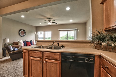 the kitchen is open to the living room with a couch and a ceiling fan