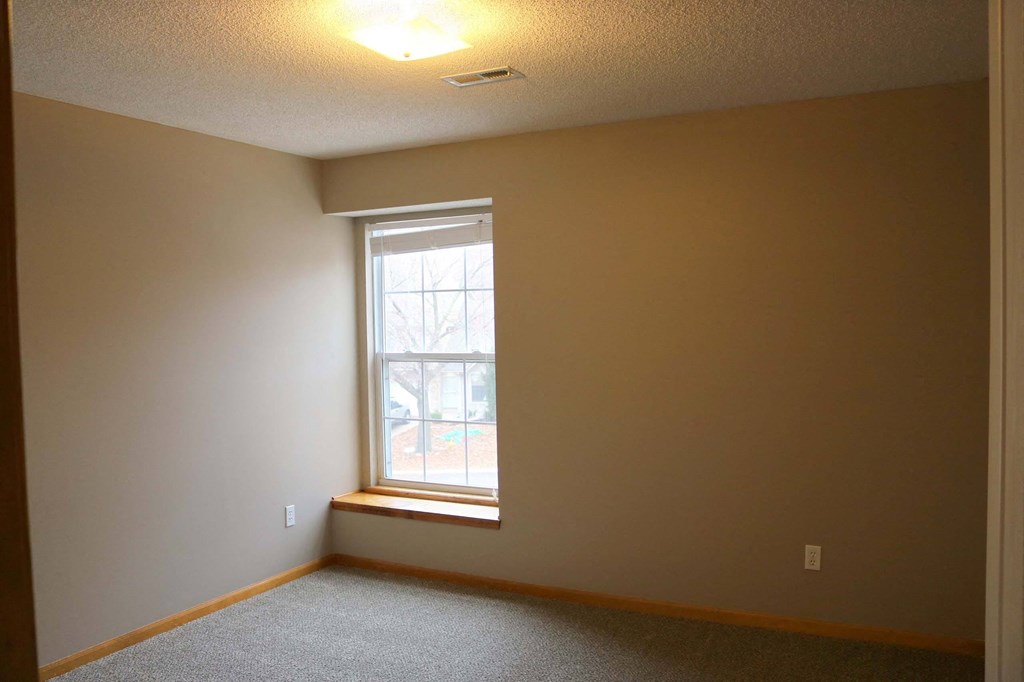 a bedroom with a window and a carpeted floor