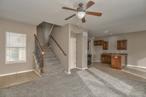 A living room with a staircase and a ceiling fan.