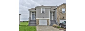 a gray house with a car parked in a driveway