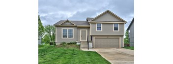 a tan house with a driveway and a garage door