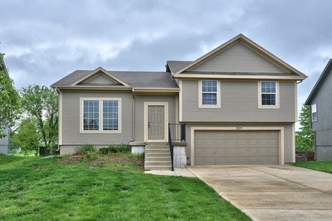 a tan house with a driveway and a garage door