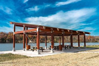 a picnic shelter with benches by a lake