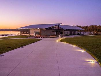 a driveway leading to a building with lights on it