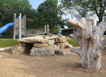 a stone bench and tree stump in a park