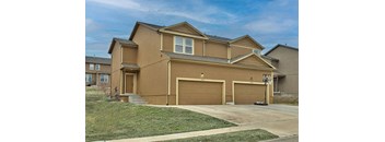 a brown house with three garages and a blue sky