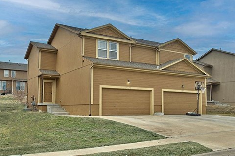 a brown house with three garages and a blue sky