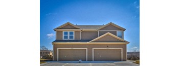 a brown house with two garage doors