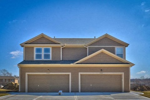 a brown house with two garage doors