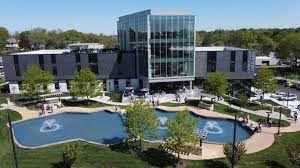 an aerial view of a campus with two swimming pools    and a building