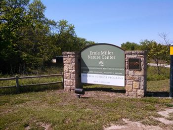 a sign for the erie mill nature center in front of a fence and trees