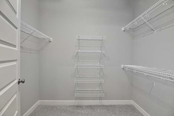 a walk in closet with empty shelves and a door