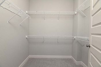 an empty closet with white shelves and a white door