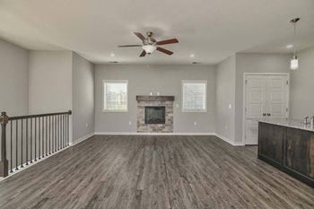 an empty living room with a ceiling fan and a fireplace