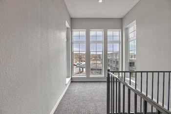 a living room with a view of a staircase and windows