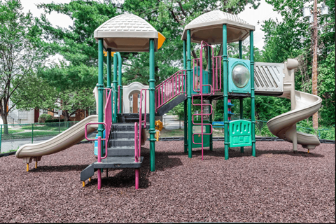 A playground with a green and pink slide and a white and green tower.
