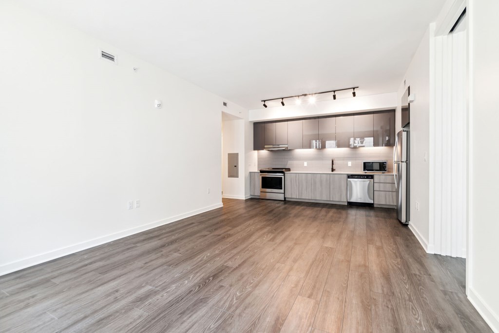 A kitchen with a white wall and a wooden floor.