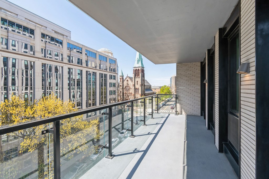 A balcony with a glass railing overlooks a city street.