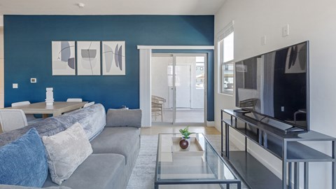 A modern living room with a grey sofa and a glass coffee table.