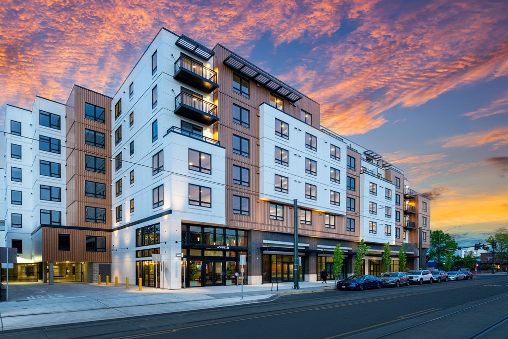 A modern apartment building with cars parked in front.