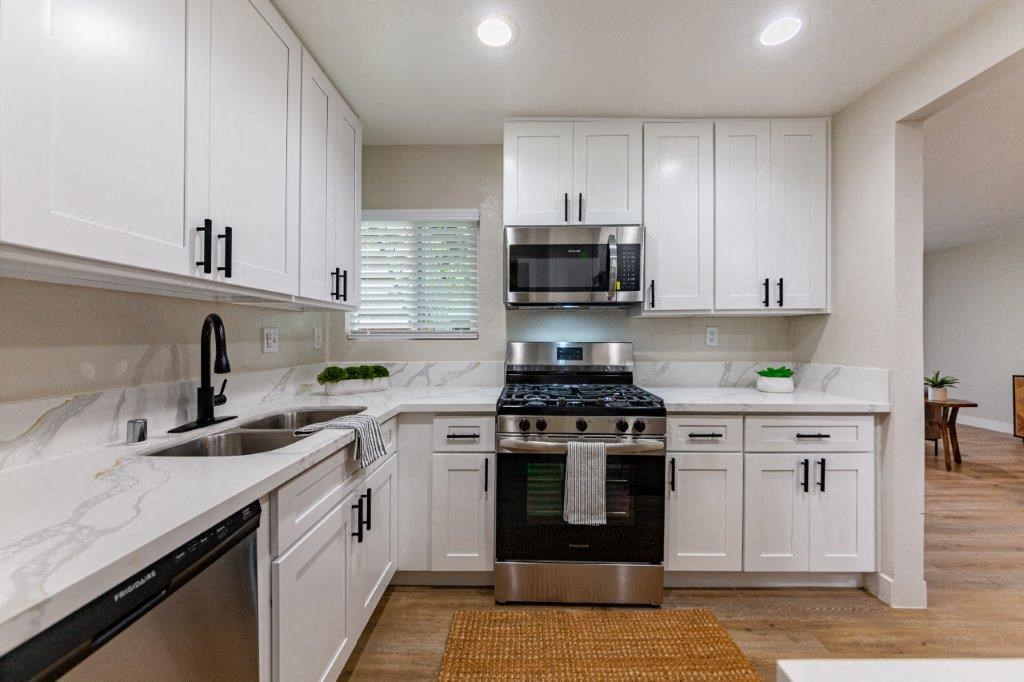 a white kitchen with white cabinets and a black stove