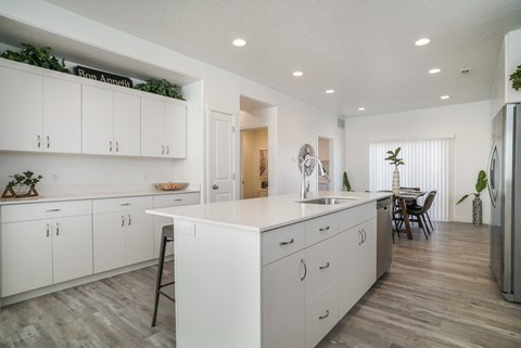an open kitchen and dining room with white cabinets and a white counter top