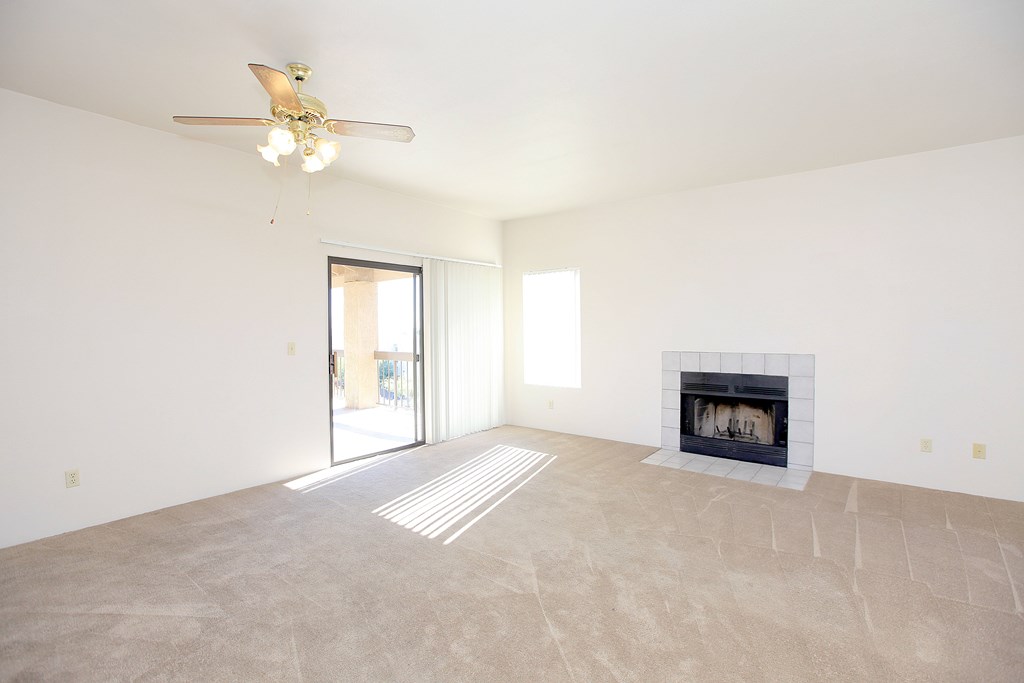 A living room with a fireplace and a ceiling fan.