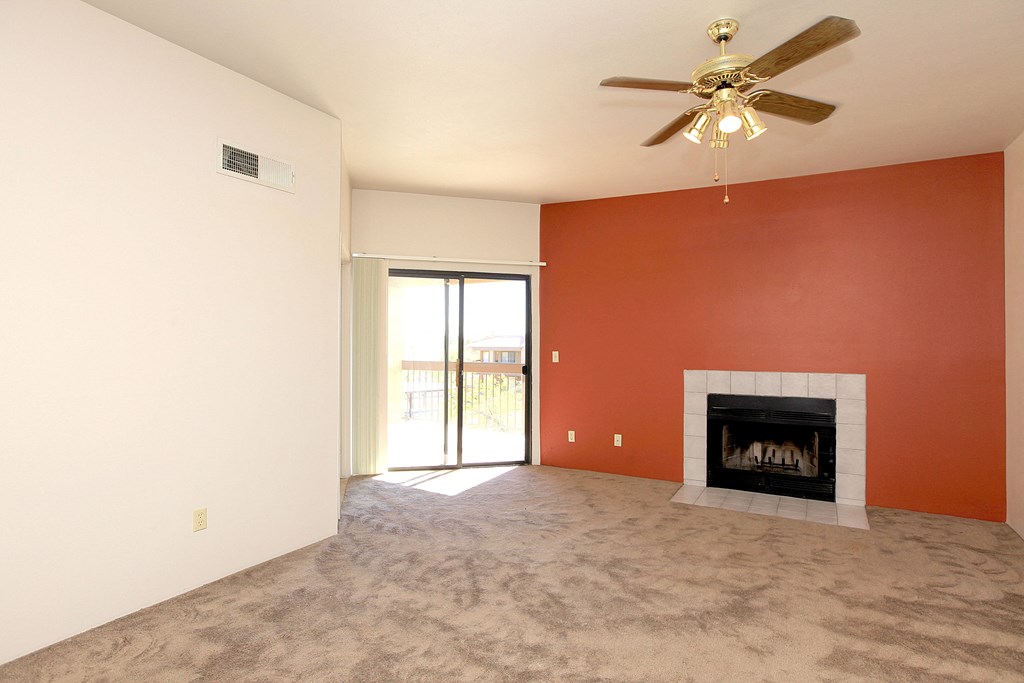 A living room with a fireplace and a ceiling fan.