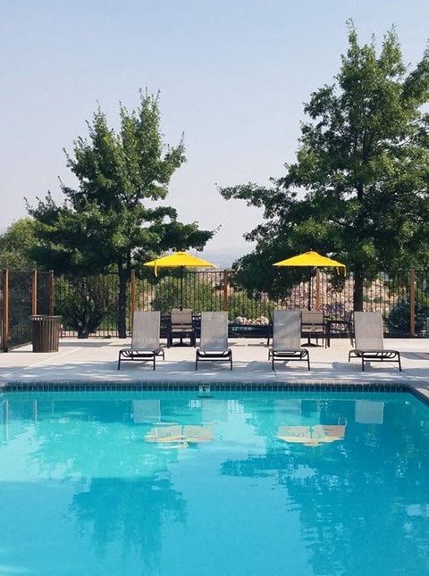 a swimming pool with chairs and umbrellas next to it