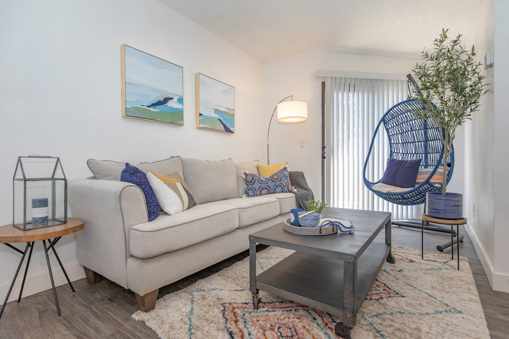A living room with a white couch, a coffee table, and a hanging chair.