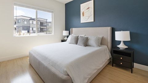 A bedroom with a large bed and a view of a building outside the window.