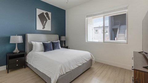 A bedroom with a bed, two lamps, and a picture on the wall.