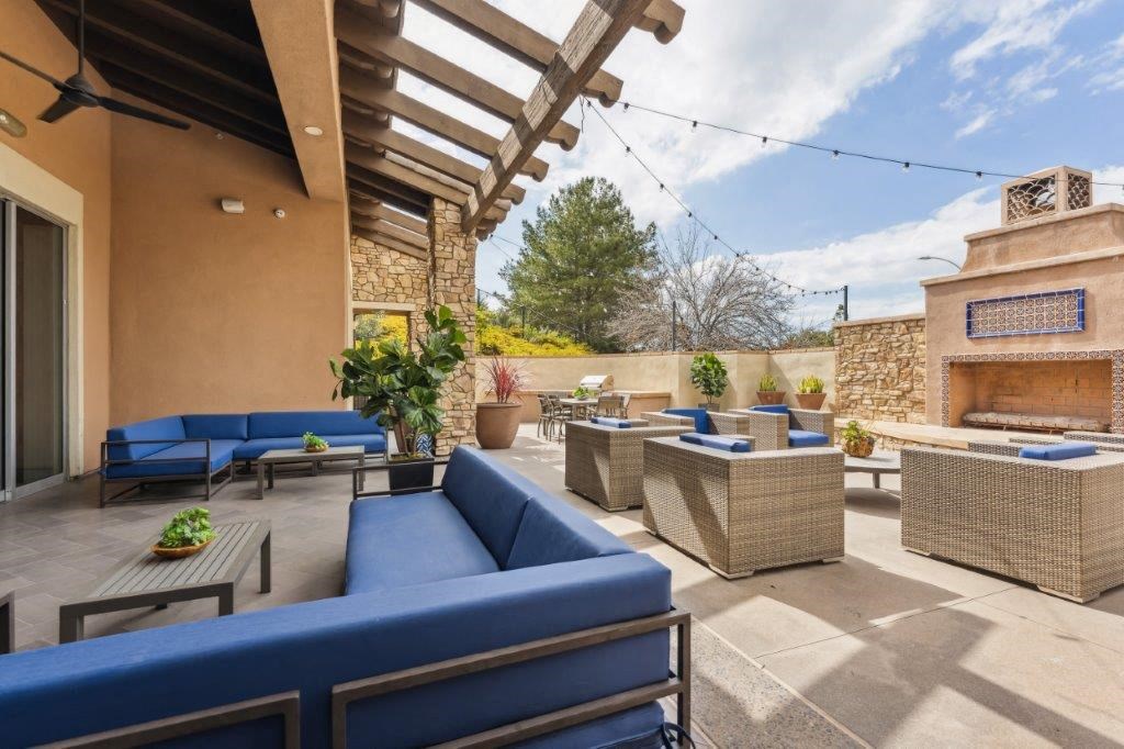 a patio with blue couches and tables and a fireplace