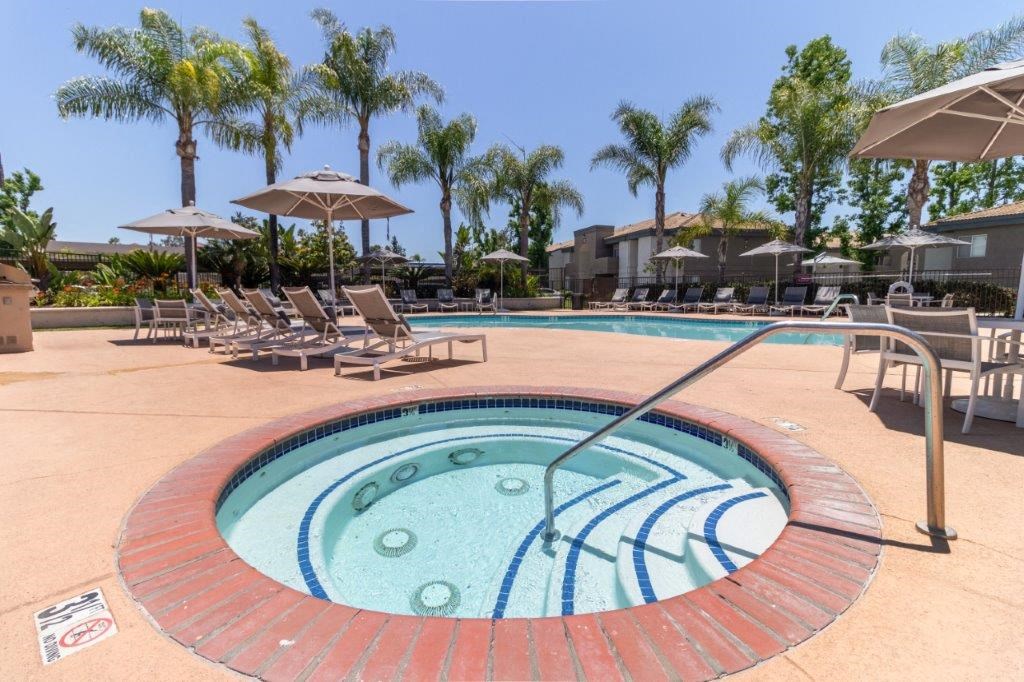 a hot tub in a pool with chairs and umbrellas