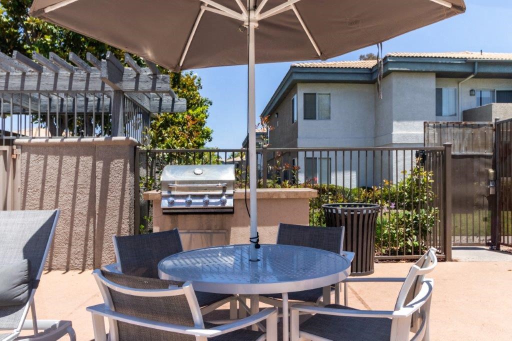 a patio with a table and chairs and a grill