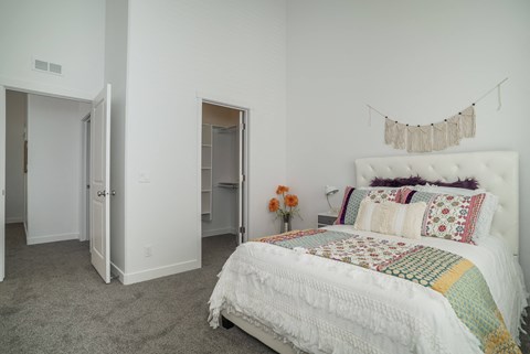a bedroom with white walls and a bed with a blanket and pillows