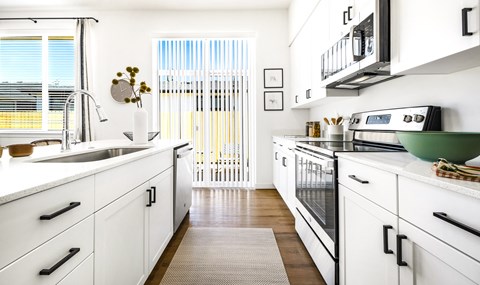 a kitchen with white cabinets and a sink and a window