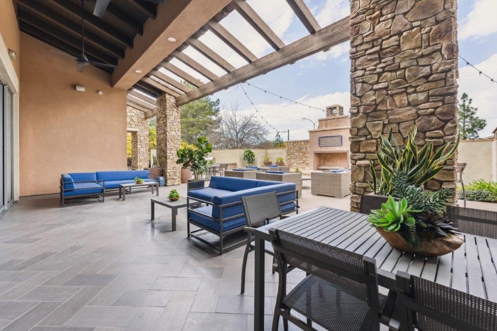 a patio with a table and chairs and a stone wall