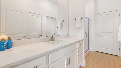A white bathroom with a sink and mirror.