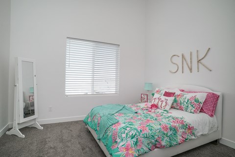 a bedroom with a bed with a tropical bedspread and pillows
