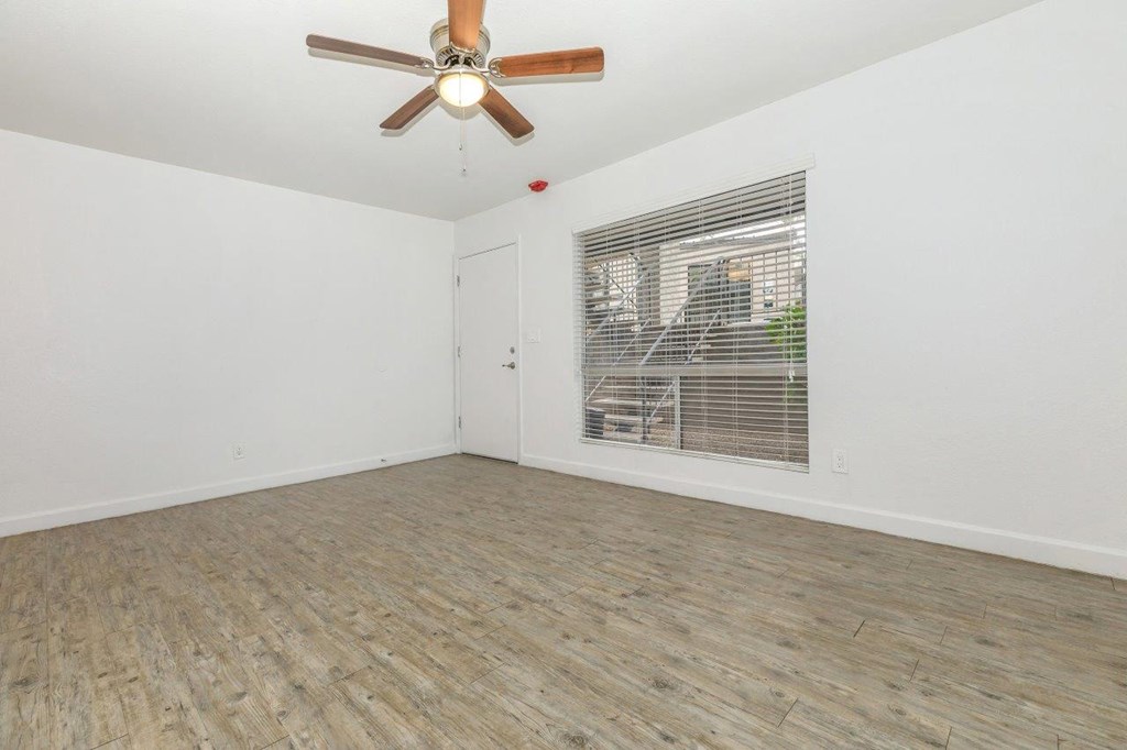 A room with a ceiling fan and a window with blinds.