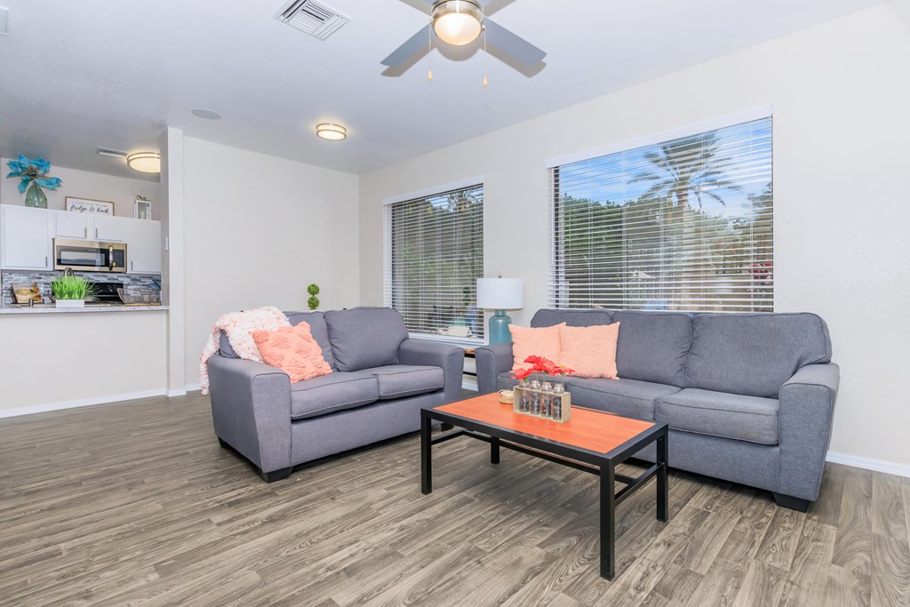 A living room with a grey couch, a coffee table, and a ceiling fan.